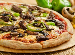 A pizza with steak, green peppers and mushrooms